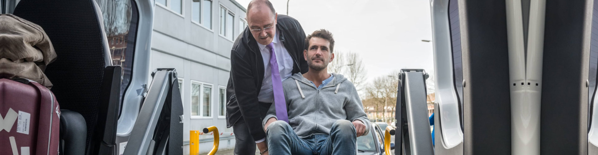 man boarding another man on wheelchair to van